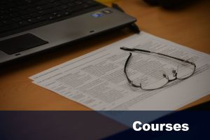 Eyeglasses lie atop papers on desk. [Text reads: Courses. | Links to information about Ed.D. courses.]